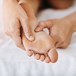 masseuse pressing patients foot