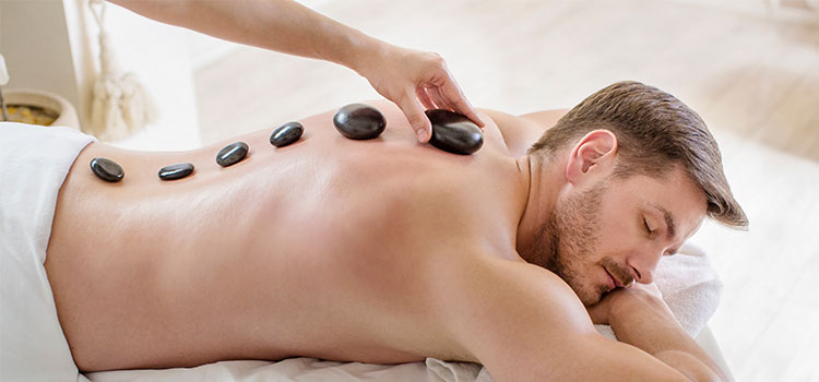 man having hot stones placed along spine
