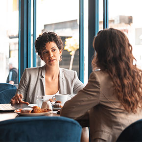 two professionals talking at cafe table with snacks and coffee