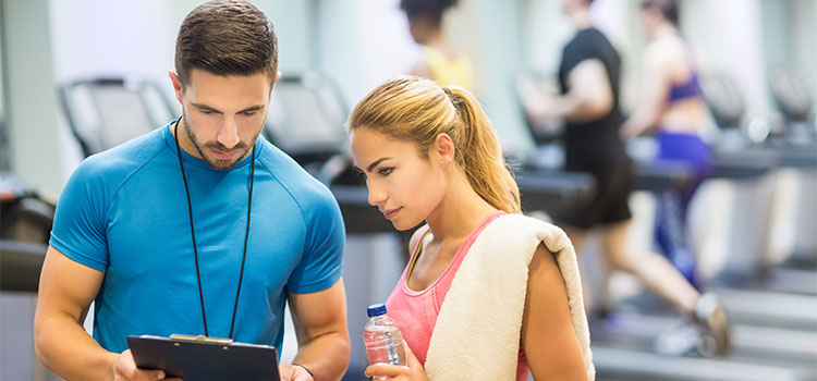 man and woman confer in busy gym