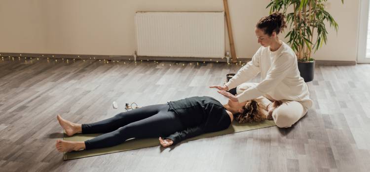 a reiki practitioner at work on a client laying flat on the floor in a studio