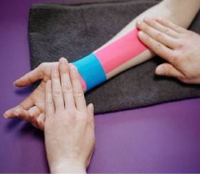 kinesiologist applies pressure to clients taped forearm