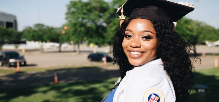 woman with a graduation cap and gown on smiling at camera