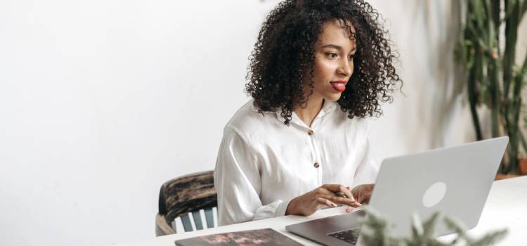 woman-with-curly-hair-sitting-at-desk-working-on-laptop