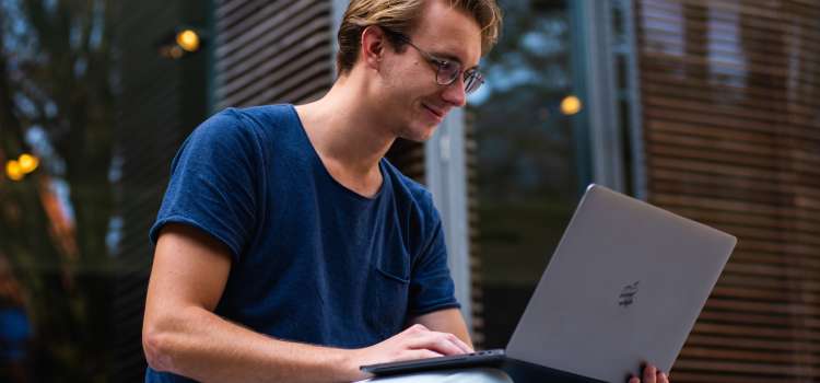 student with glasses on laptop smiling