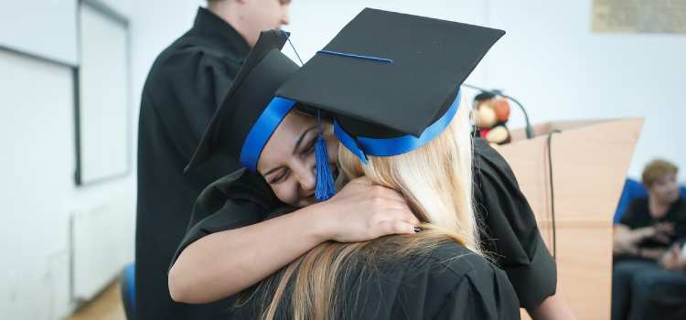 two female college graduates hug each other at commencement