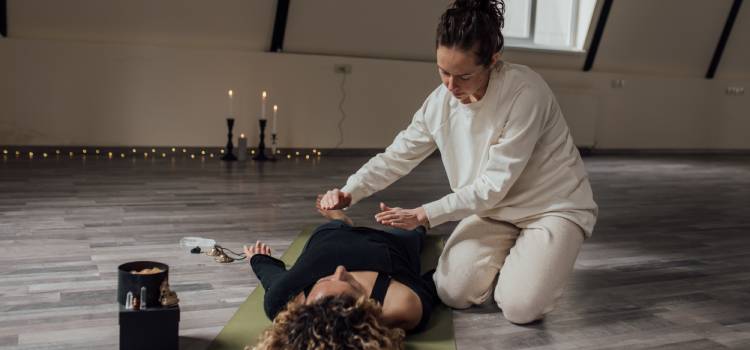 a spiritual healer with her hands hovering over a client laying on the floor