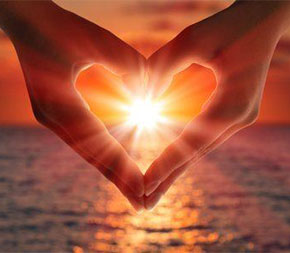 hands being held in the shape of a heart with sun shining behind