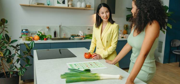 a nutritionist and her client standing at a kitchen island with produce