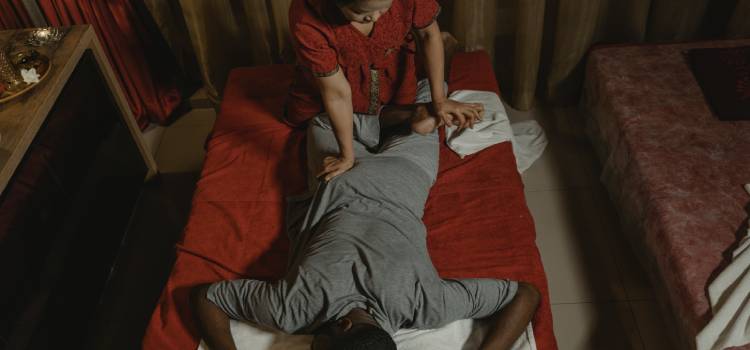 thai massage therapist pushing her right palm into patients lower back