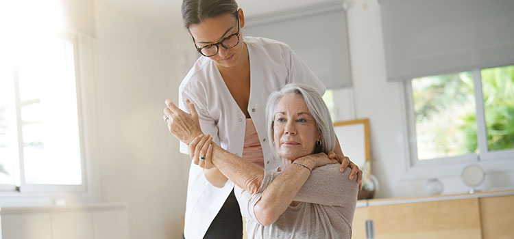 chiropractor works with older woman to help frozen shoulder