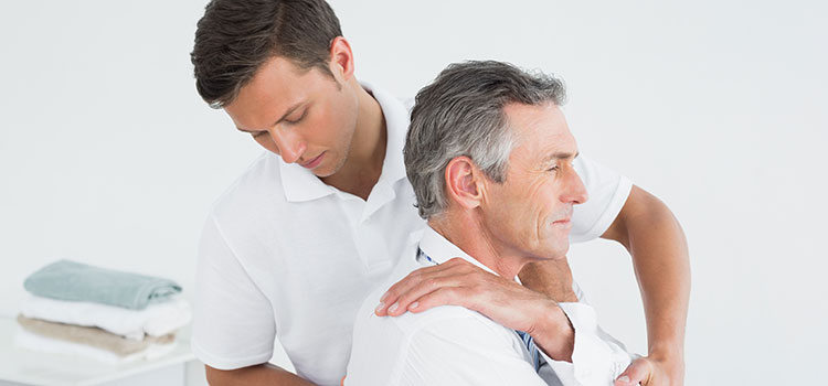 chiropractor steadies male client core to crack spine