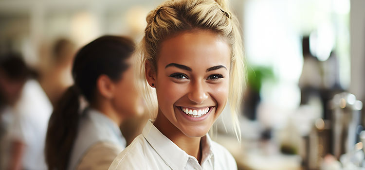 smiling esthetician student in classroom with mirror and tools
