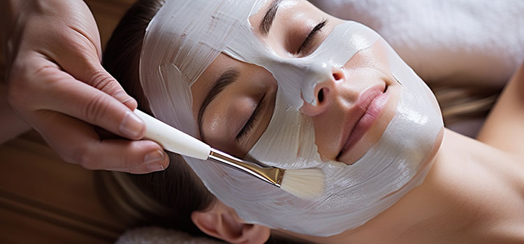 esthetician hands putting masque on womans face during facial
