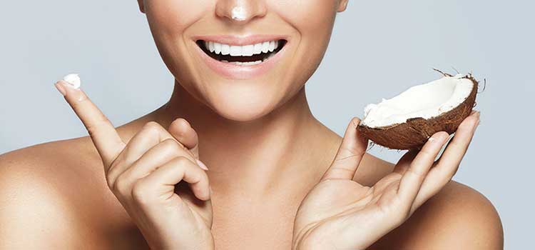 smiling face with hands holding coconut and cream made from coconut oil