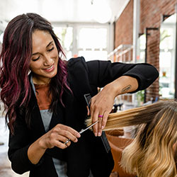 cosmetologist cuts clients hair in salon