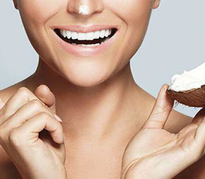 smiling face with hands holding coconut and cream made from coconut oil