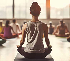 meditation teacher sits behind class od meditation students