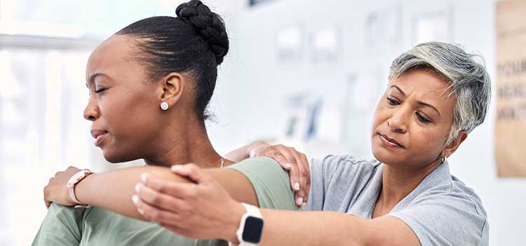female chiropractor performs shoulder adjustment on patient