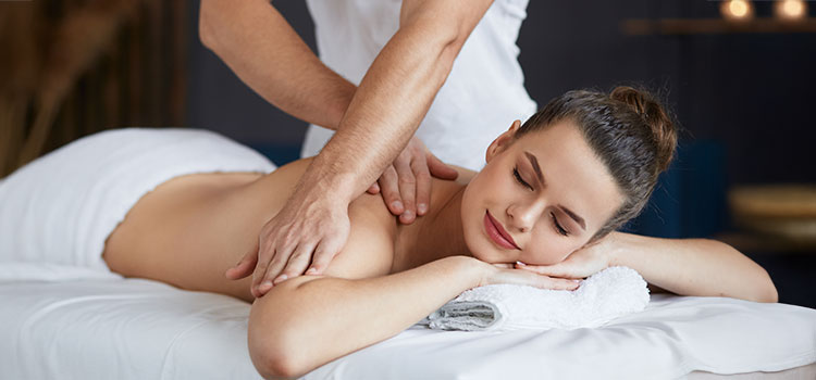 massage therapist giving massage to reclining woman