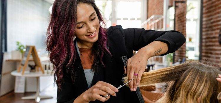 cosmetologist cuts a client's hair in a beauty salon